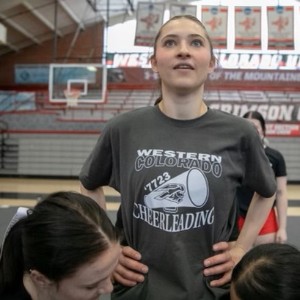 Cheerleader standing with hands on hips, wearing a T-shirt that says "Western Colorado Cheerleading"